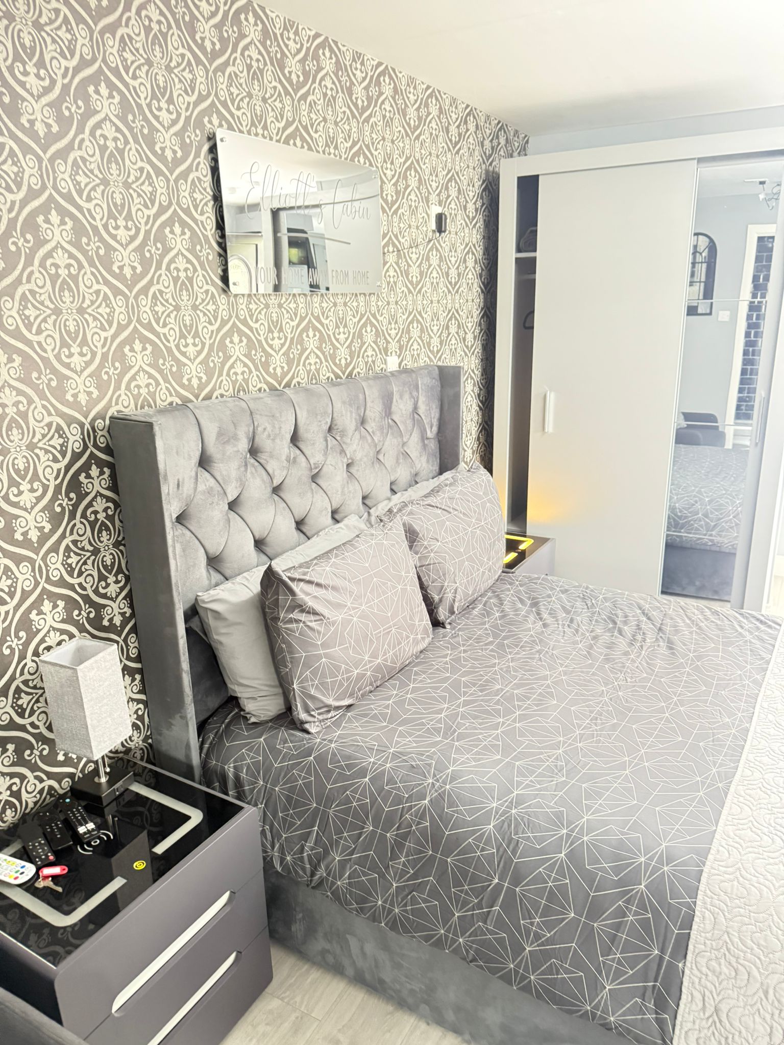 Luxurious bedroom with grey velvet bed at Elliott's Cabin